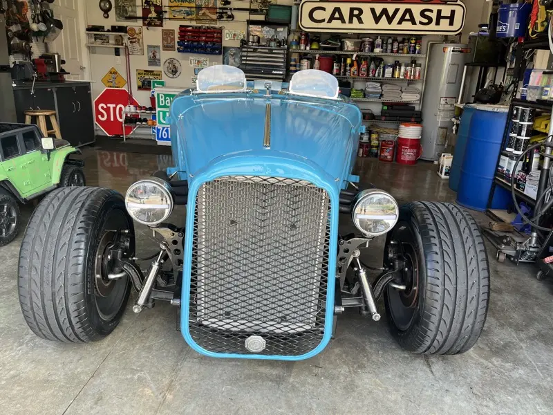 Blue hotrod roadster front view with mesh grille and exposed front suspension