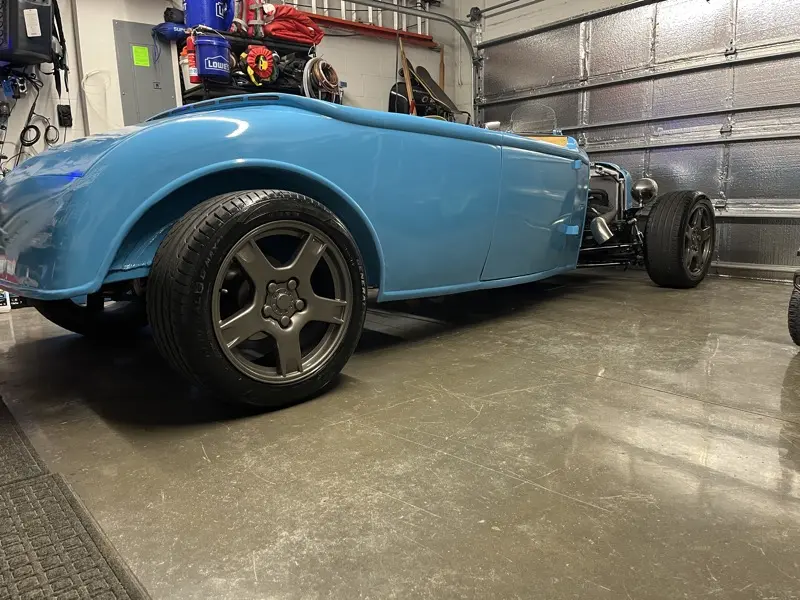 Blue hotrod roadster side profile in the garage with Corvette-style wheels