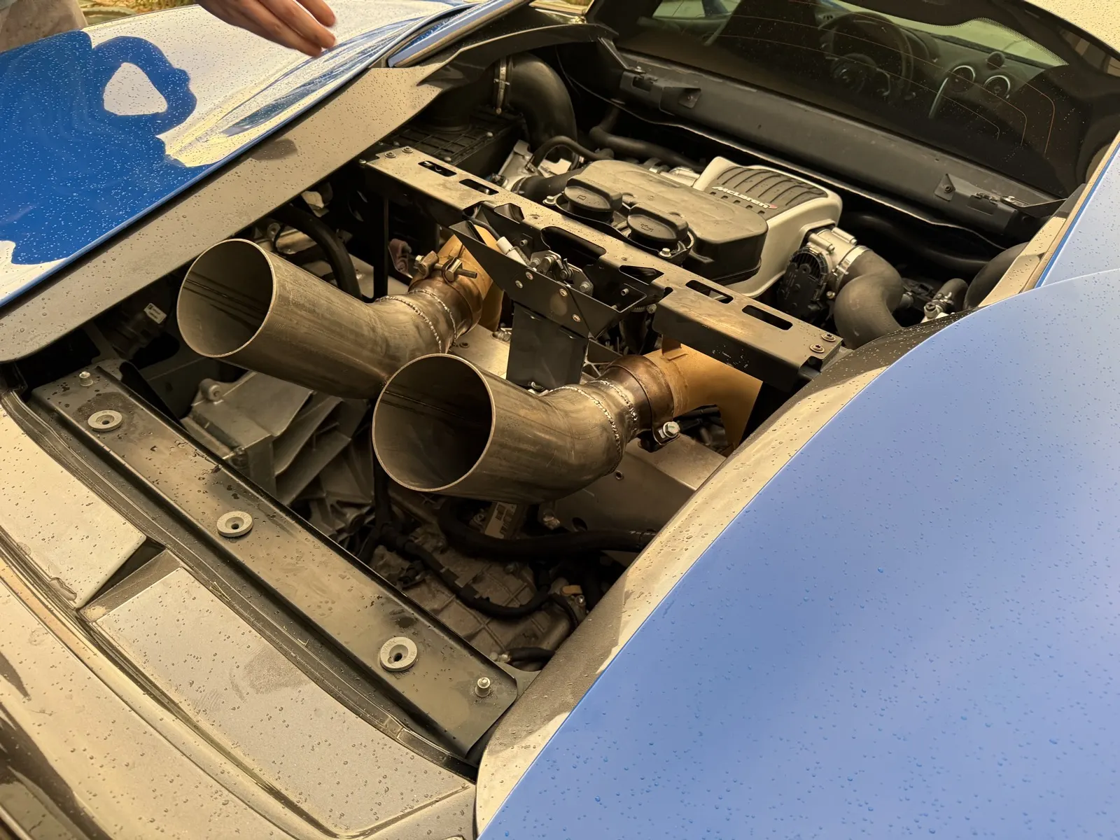 Custom stainless exhaust tips with hand-welded seams installed in a McLaren 570S engine bay