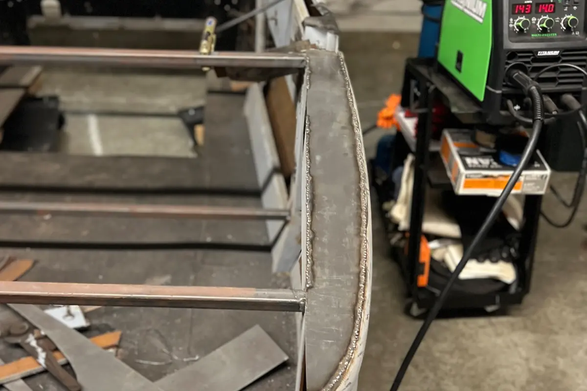 Welded steel frame rails and TIG welder in the shop