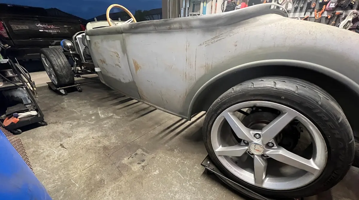 Bare-metal hotrod roadster body on dollies with polished wheels